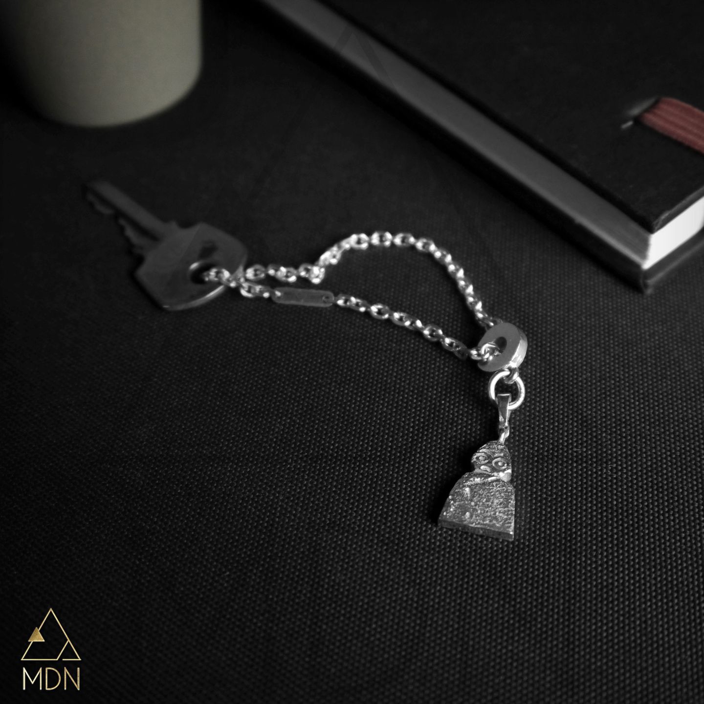 Bracelet with silver-toned evil eye charm and chain on black background.