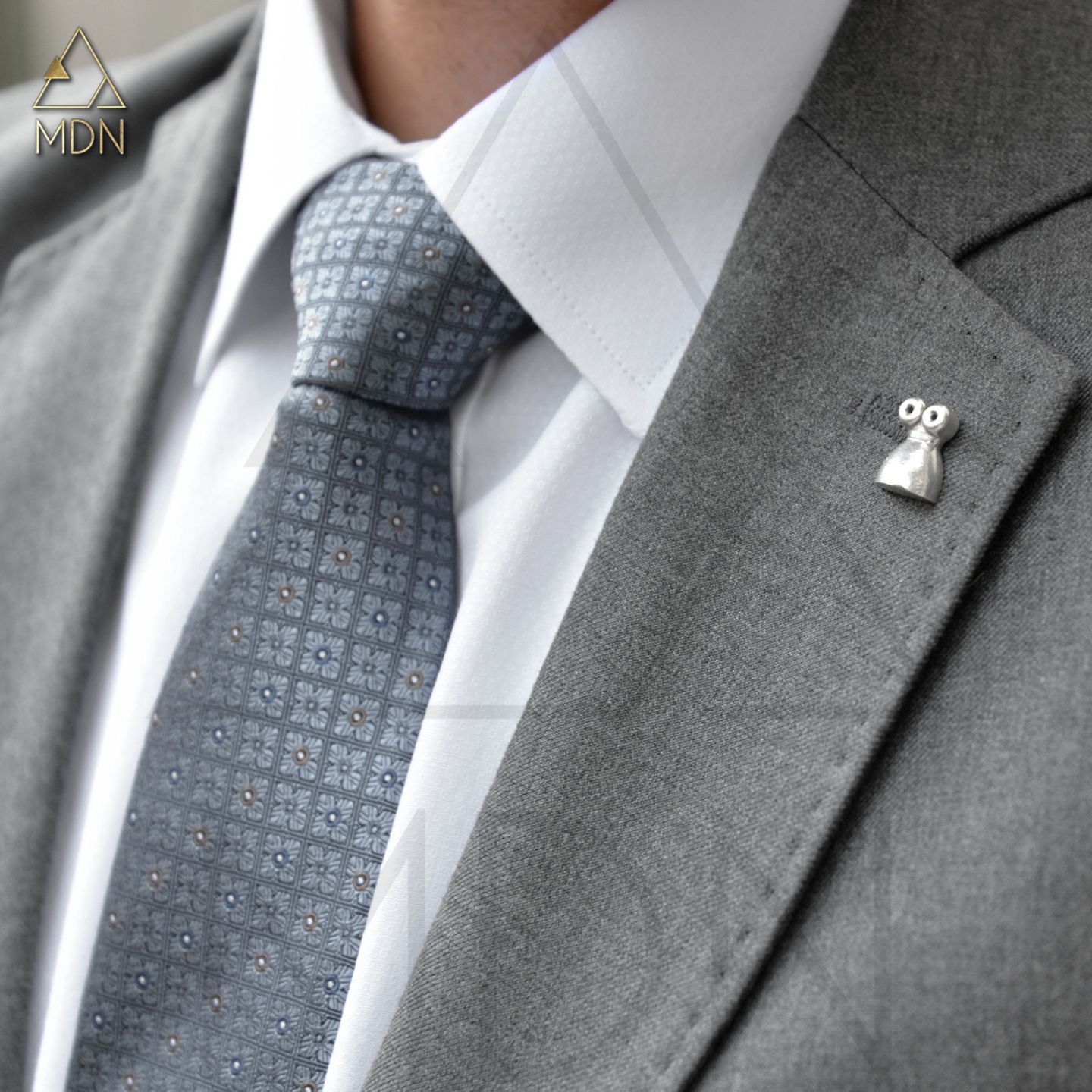 Silver-toned evil eye brooch on jacket lapel.