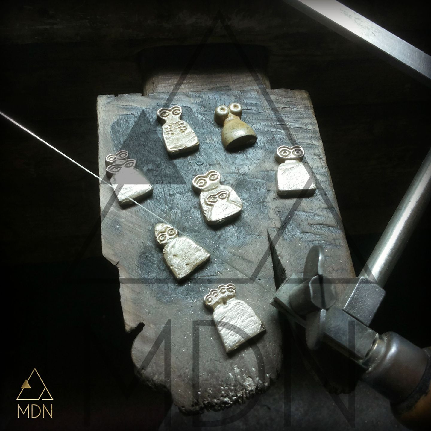 Multiple evil eye pendants and charms in silver-toned metal displayed.