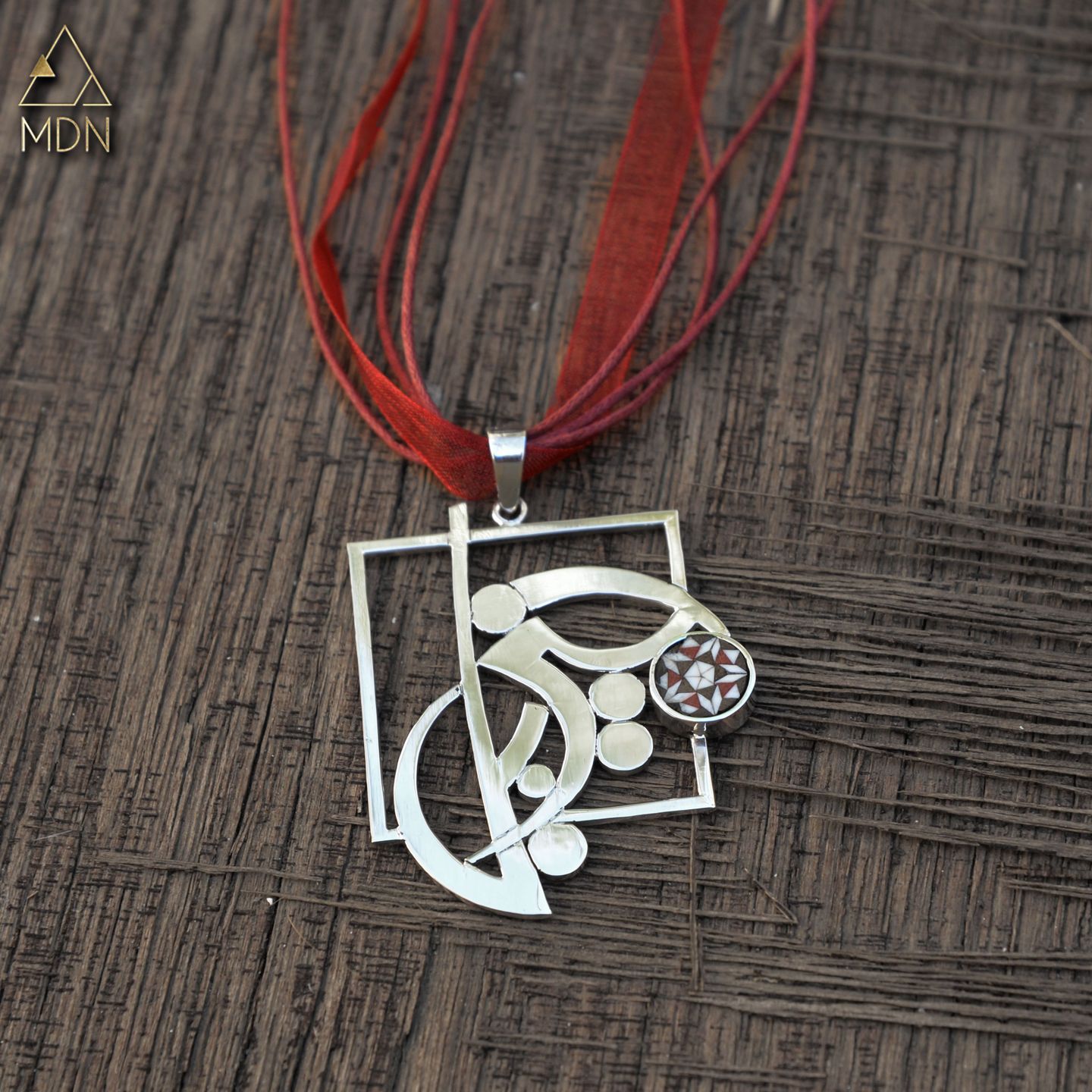 Pendant rendering the name Jizel in Arabic calligraphy on red cord.