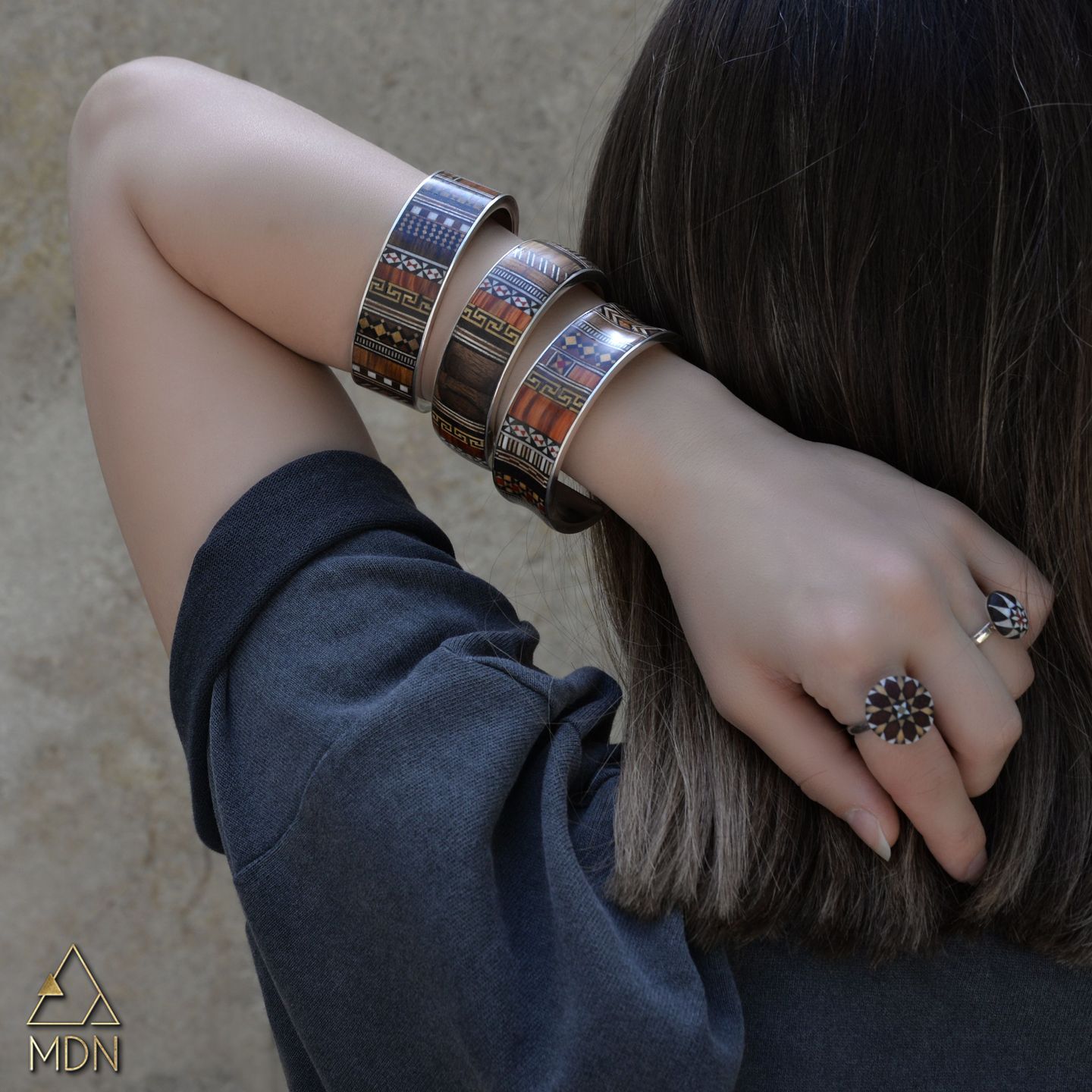 Multiple mosaic inlay bracelets on wrist.