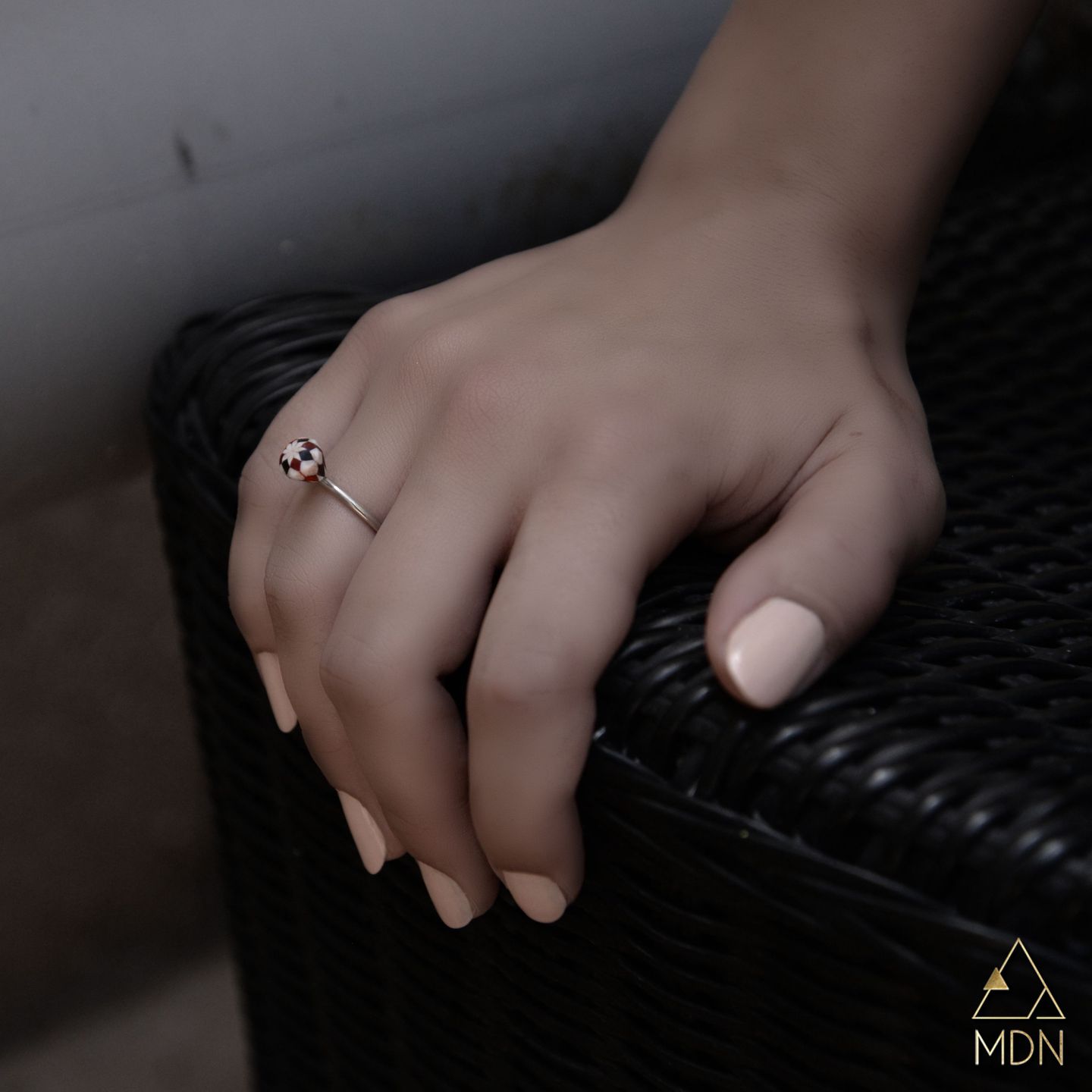 Small ring with mosaic inlay geometric pattern worn on finger.