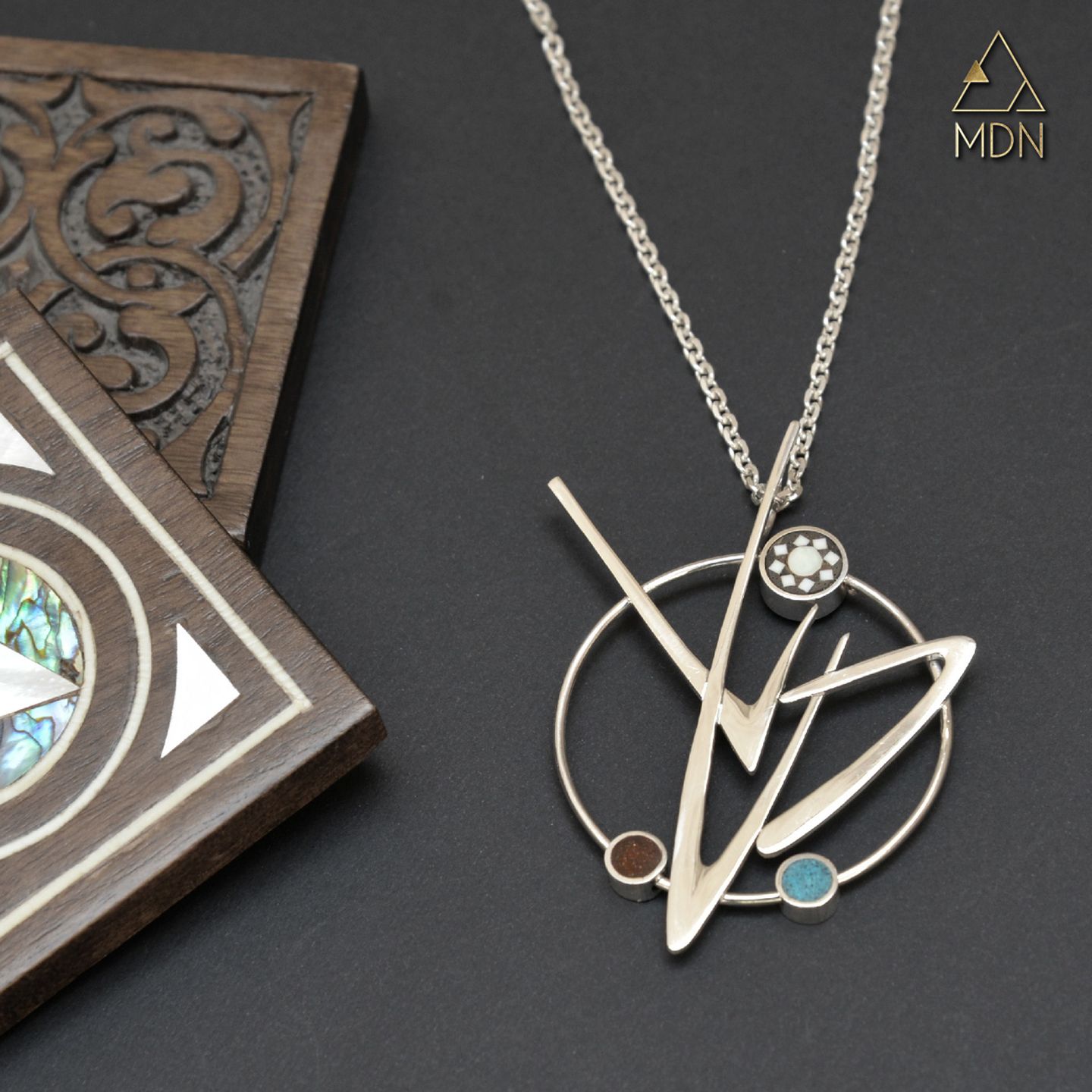 Geometric pendant with blue stone inlay.
