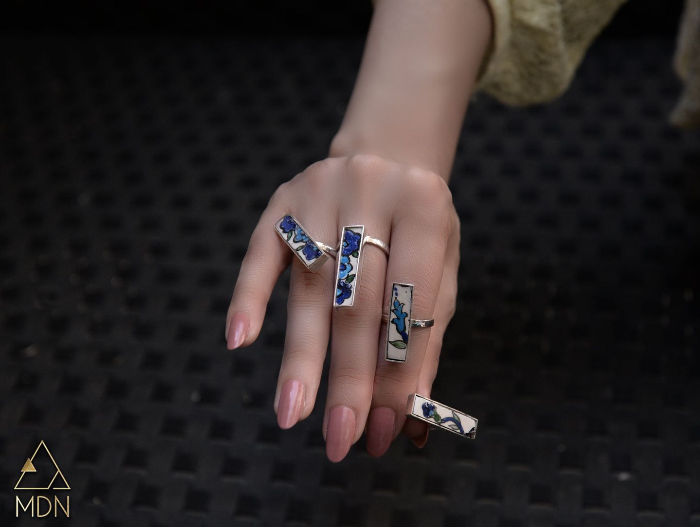 Mosaic inlay rings displayed on hand.
