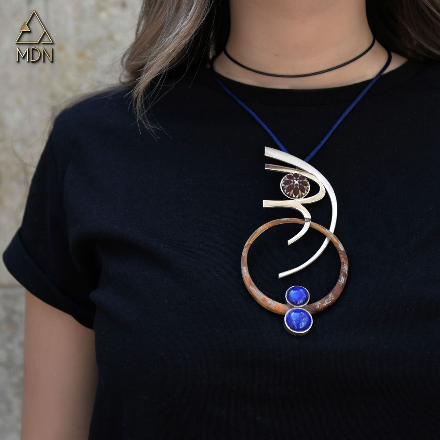 Pendant rendering the name Randa in Arabic calligraphy with blue stones.