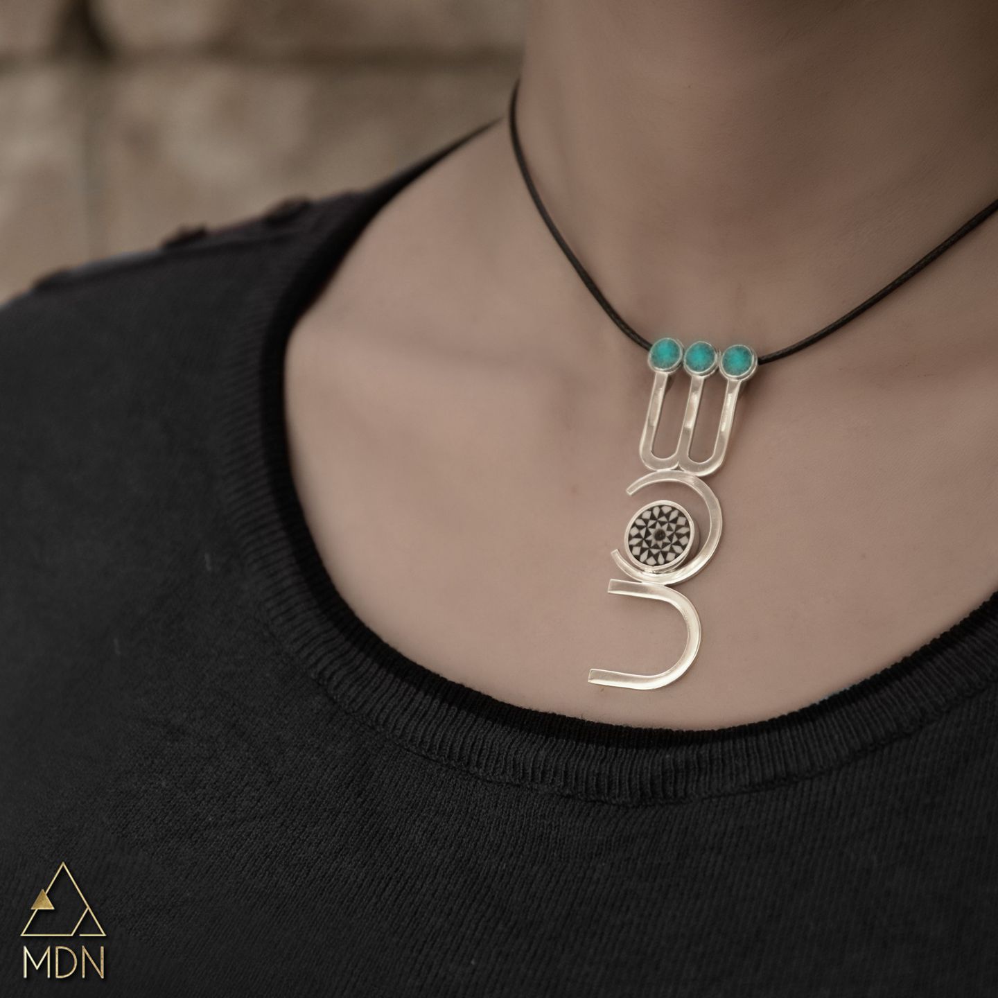 Pendant rendering the name Shahed in Arabic calligraphy with turquoise.