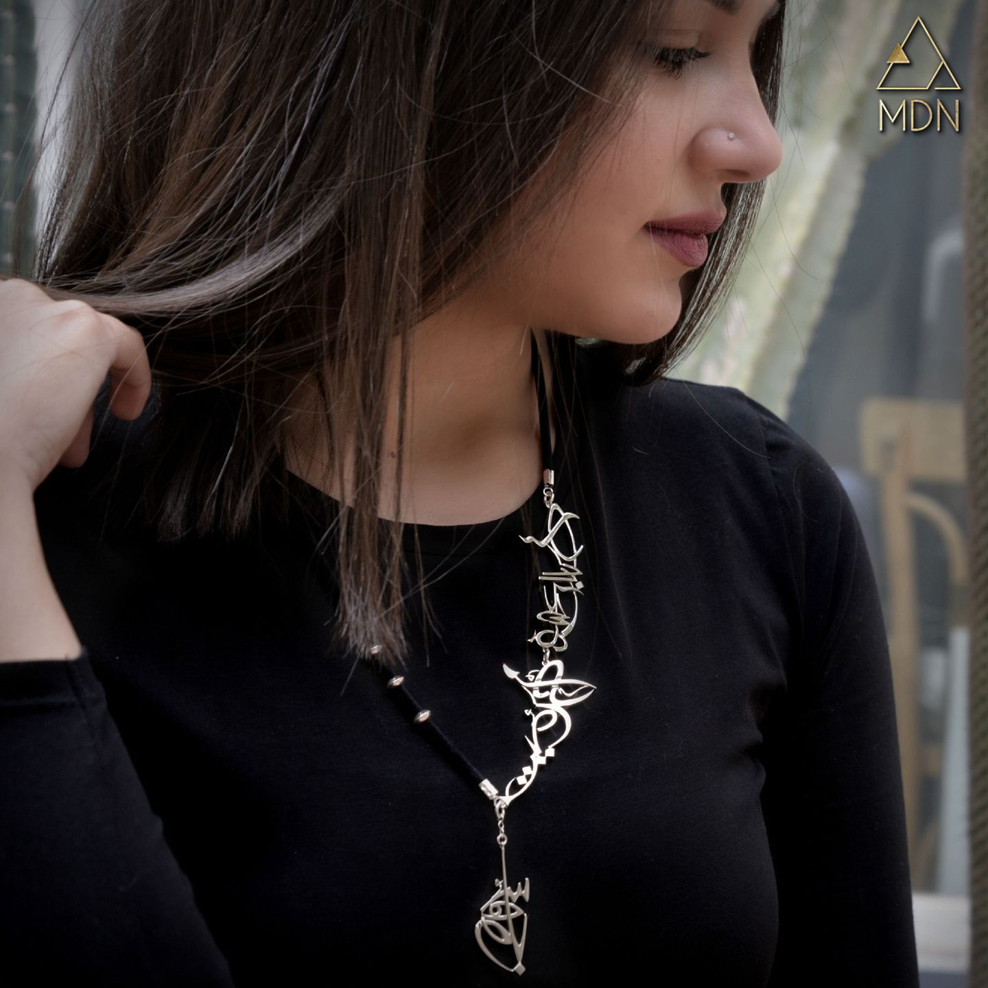 Woman wearing pendant necklace with Arabic calligraphy.