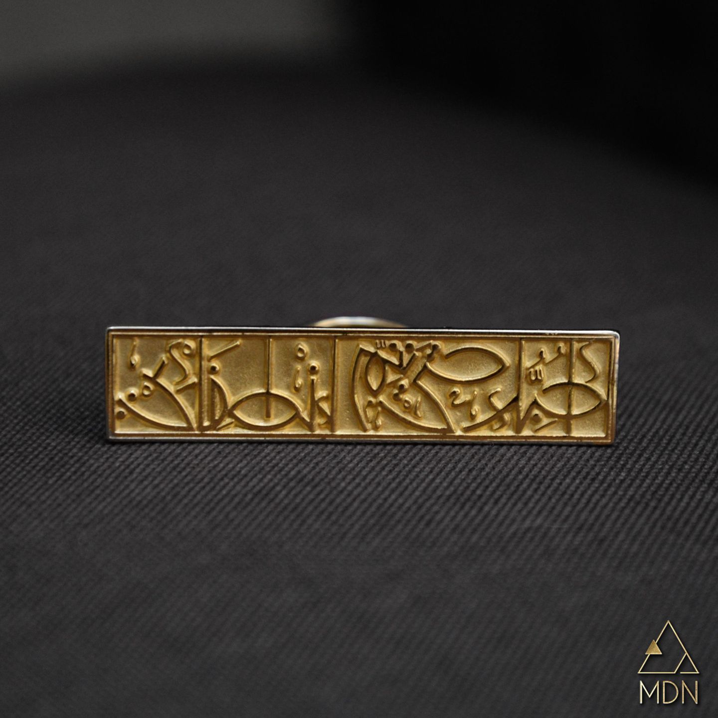 Cuff with Arabic calligraphy "احبك حتى يتم انطفائي" in gold-toned metal.