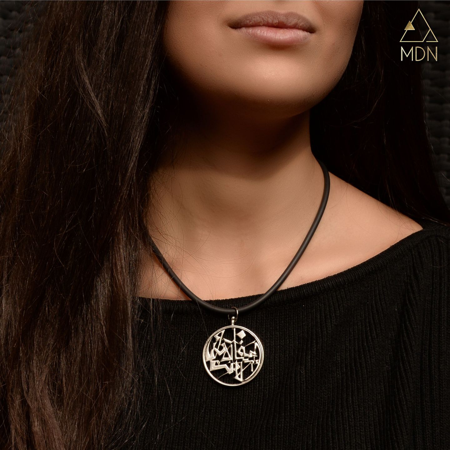 Pendant with Arabic calligraphy "الساعة الان انا الا انت" worn on person.
