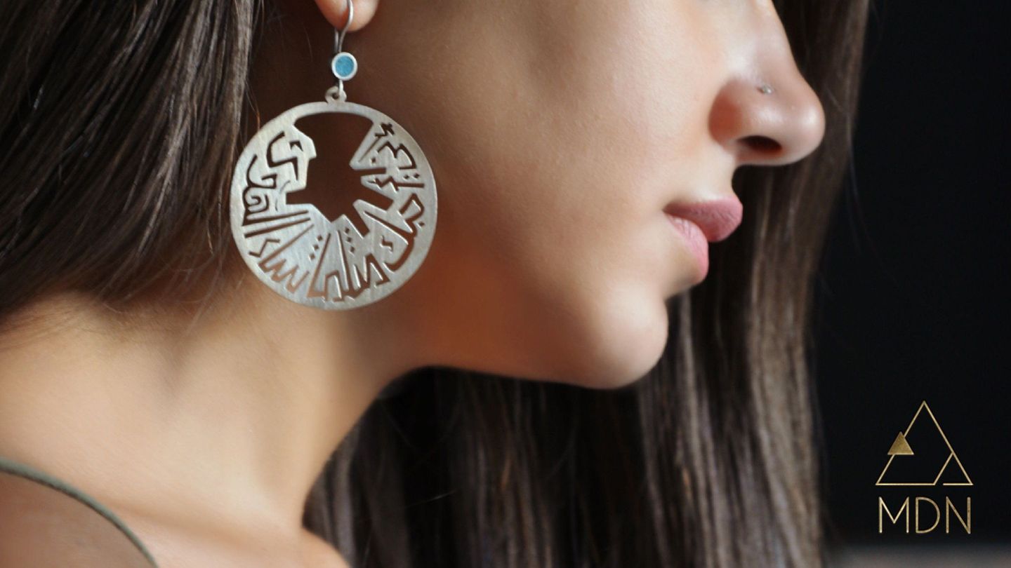 Circular earring with geometric calligraphy pattern reading "اني أحبك مثلما شاء الهوى".