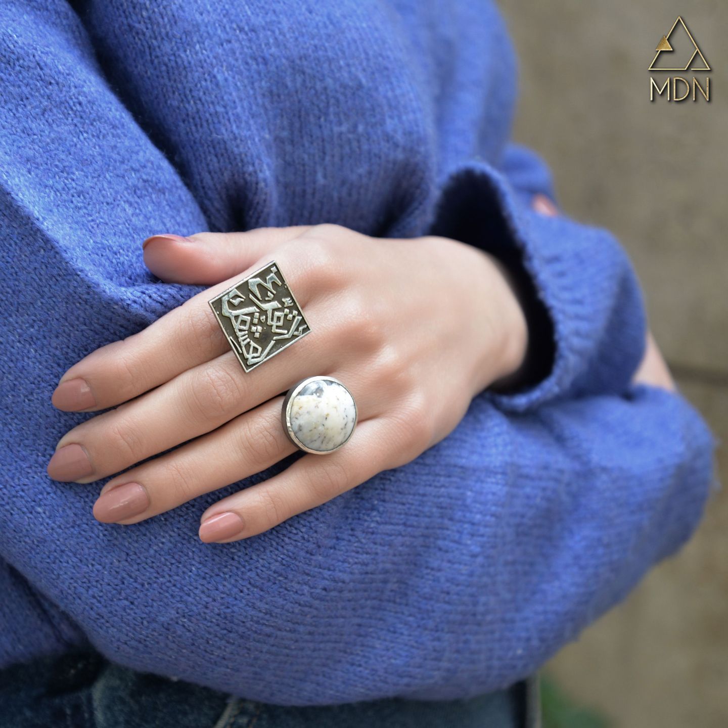 Rings with Arabic calligraphy "اتفرغ لعشقك" in silver-toned metal worn.