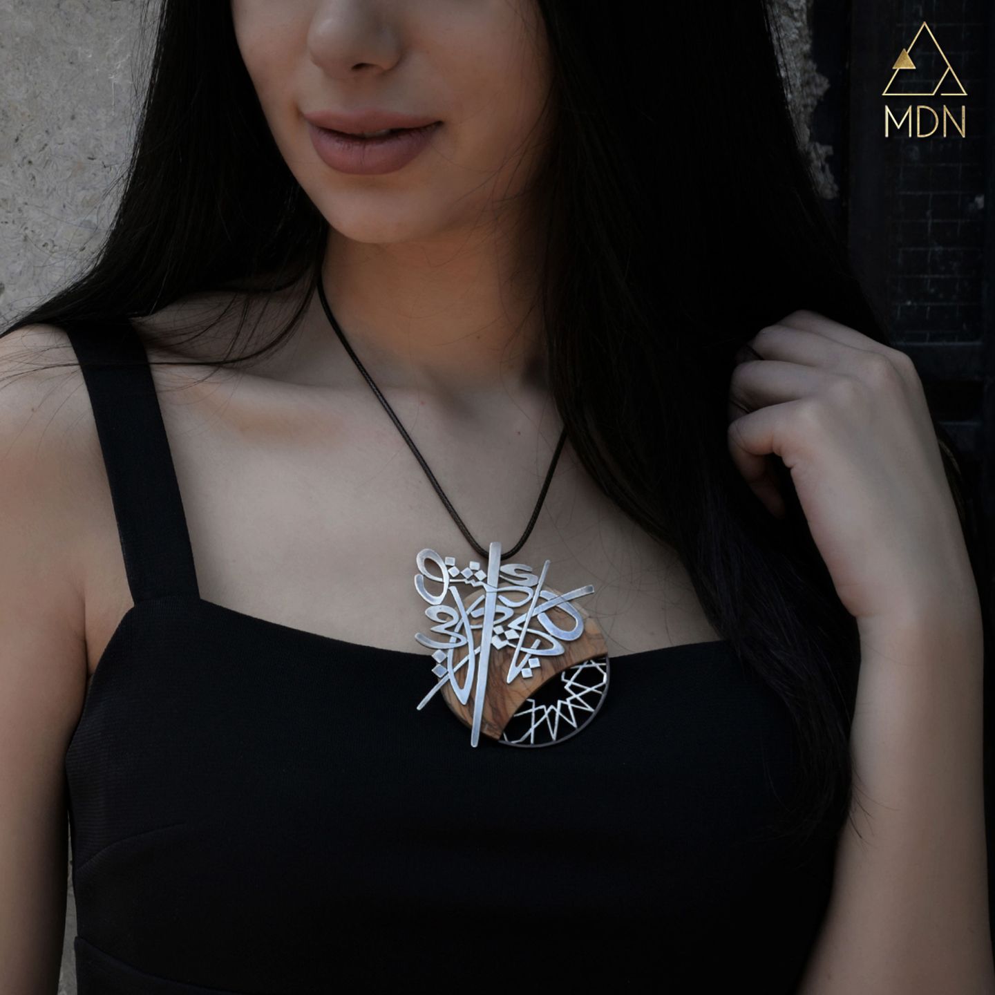 Pendant with Arabic calligraphy "دمشق يا كنز احلامي" worn on person.