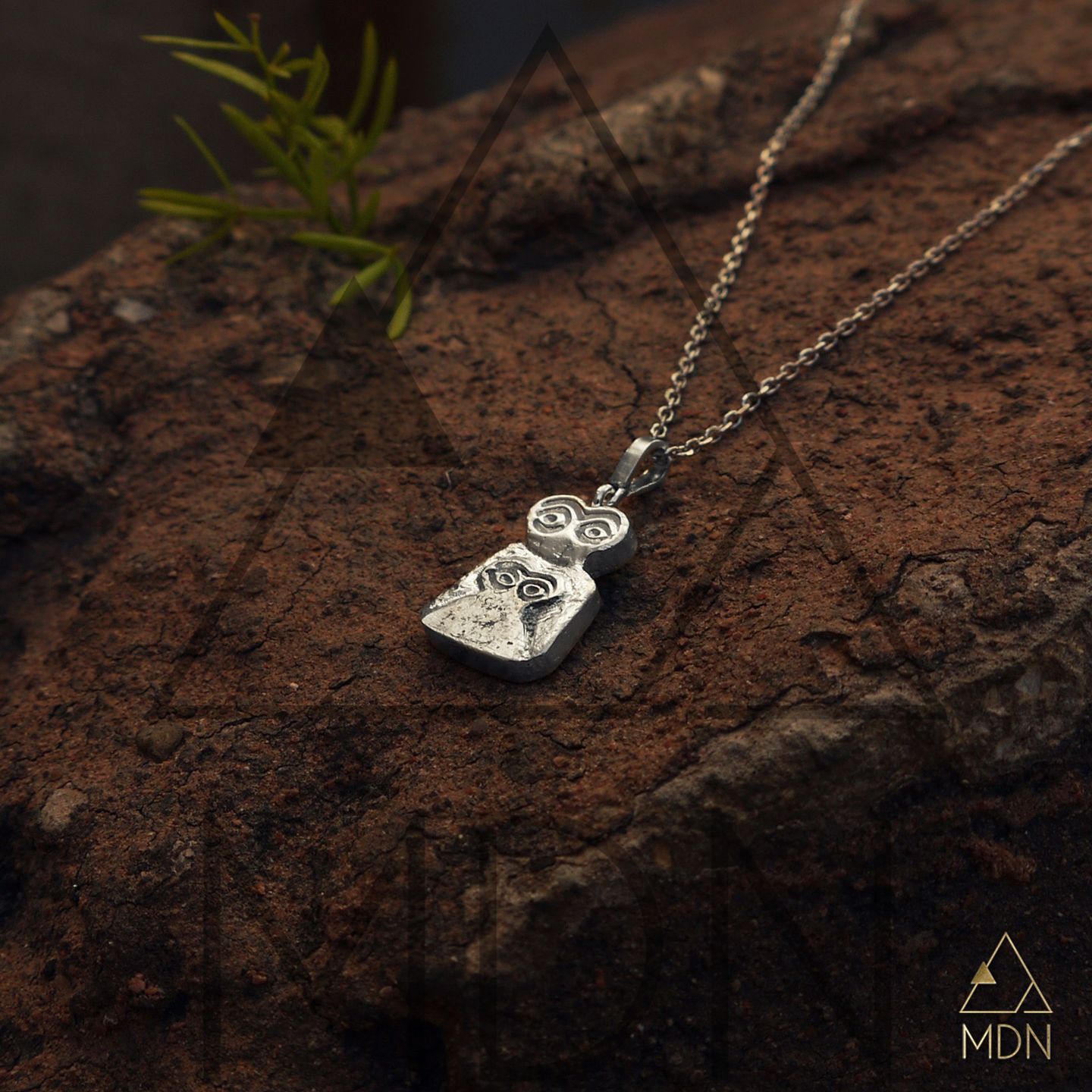 Evil eye pendant with mosaic inlay in silver-toned metal on display.