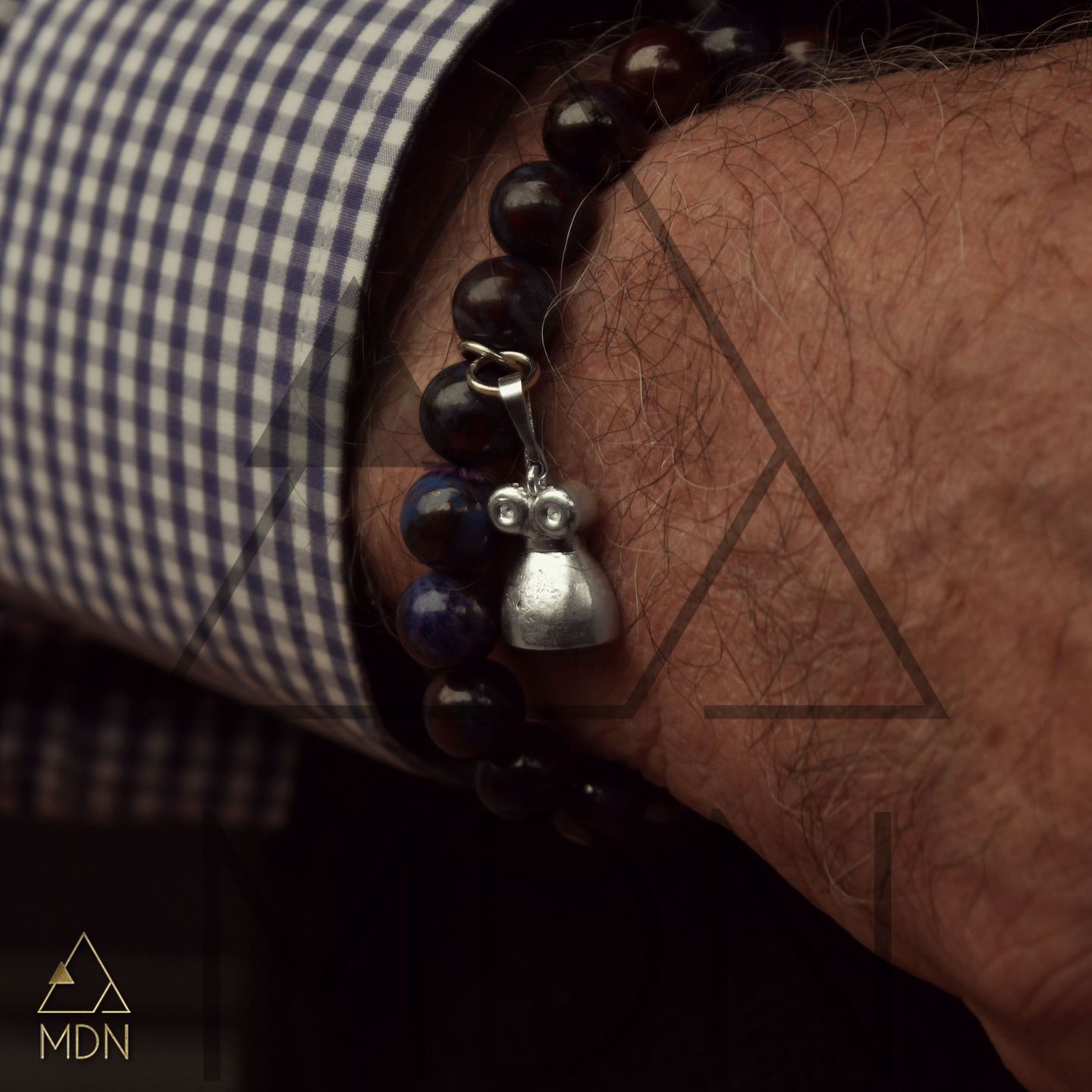 Bracelet with dark beads and metal pendant charm.