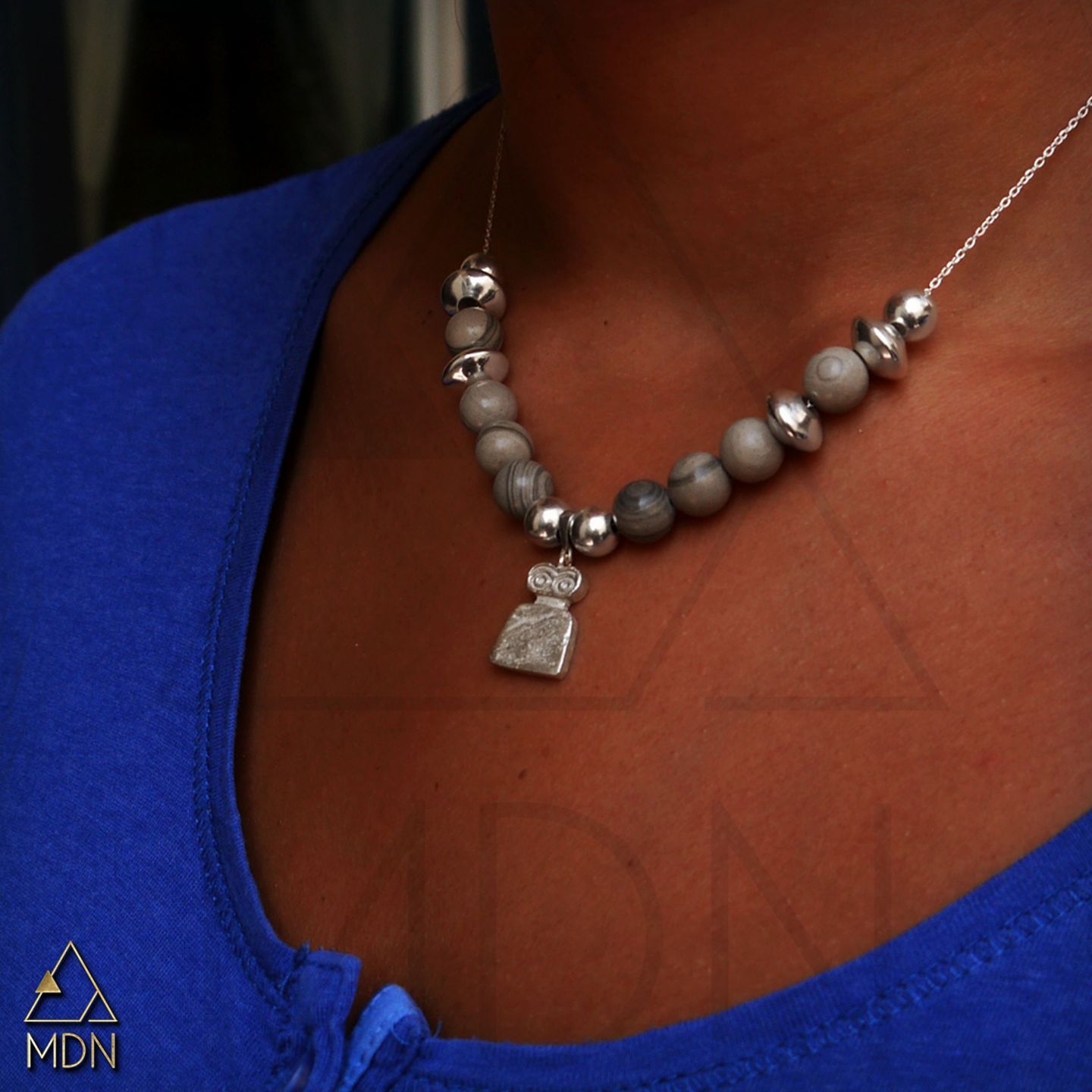 Necklace with gray beads and silver-toned evil eye pendant worn.