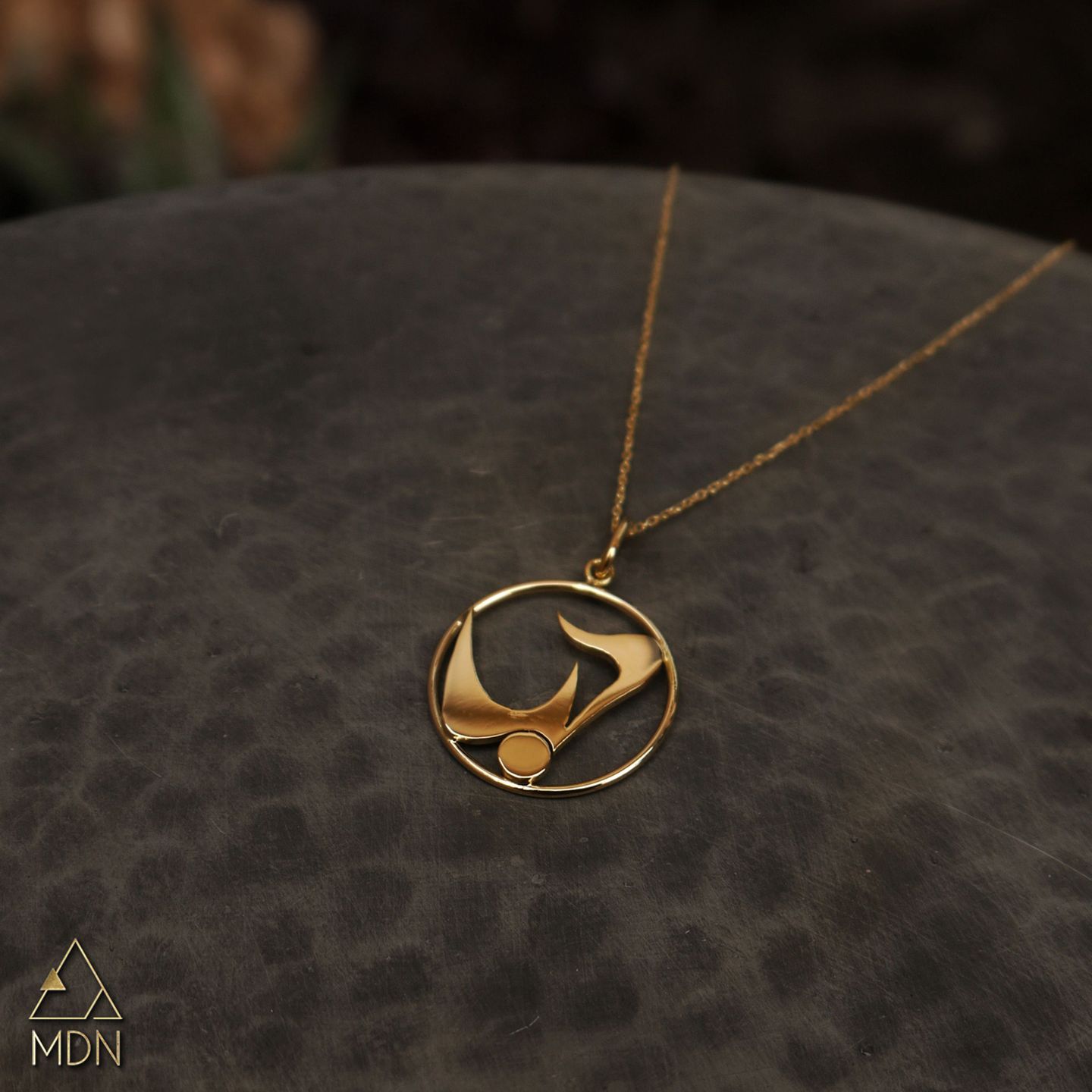 Gold-toned pendant with circular frame carrying Arabic calligraphy reading "حب".