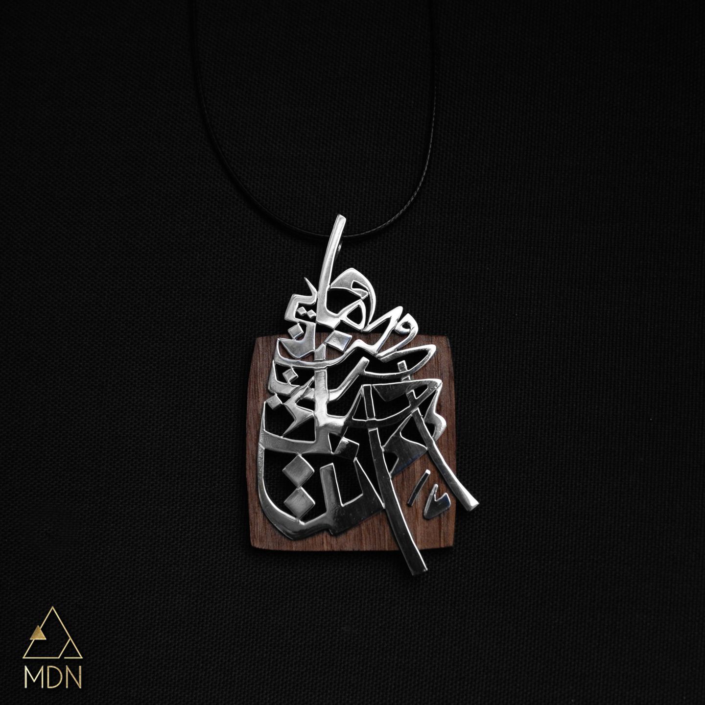 Pendant with Arabic calligraphy "و ما بين حب و حب احبك انت" and wood backing.